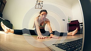 Athletic woman attends an online yoga class at home with her laptop