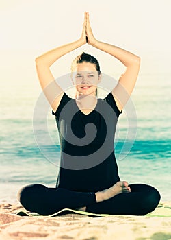 Athletic woman in black T-shirt is sitting and practicing pranayama