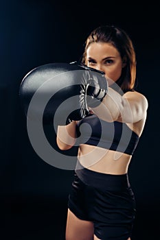 Athletic woman in boxing gloves is practicing karate in studio.