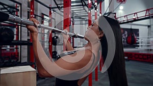 Athletic woman doing a bicep pull-up, in an indoor gym, toned and firm