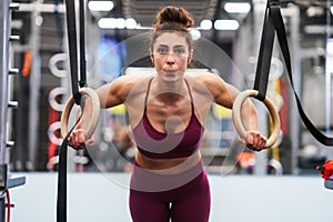 Athletic woman doing some pull up exercises in the gymnastic rings