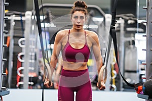 Athletic woman doing some pull up exercises in the gymnastic rings