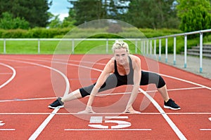 Athletic woman doing straddle stretches on track photo