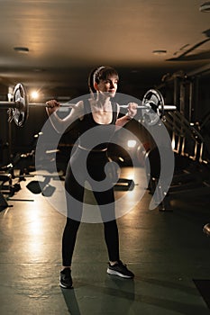 Athletic woman getting ready to do barbell squat in crossfit gym, hard workout. Sportswoman doing exercise with heavy