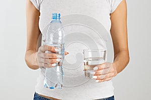 Athletic woman holding a bottle and a glass of water in her hands. Healthy lifestyle concept