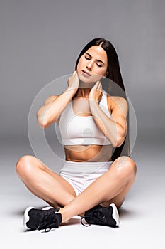 Athletic woman holding her lower back and shoulder as if experiencing pain isolated on a white background