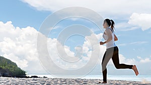 Athletic woman jogging exercise and relax and freedom on sand beach. People running and workout blue sky background.