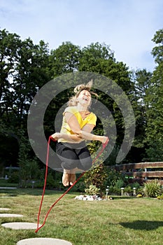 Athletic woman jumping rope in the garden