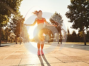 Athletic woman with jumping rope training in park