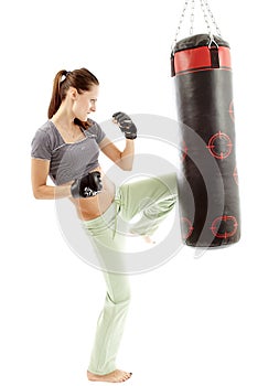 Athletic woman kicking the punching bag