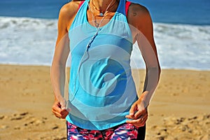 Athletic woman listening music on beach
