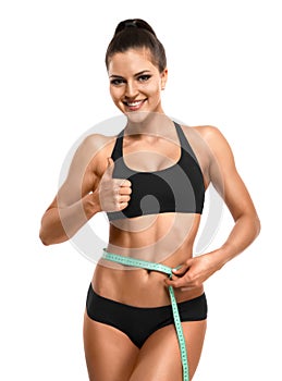 Athletic woman measuring her waist and showing thumb up isolate