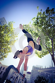 Athletic woman performing handstand on bar