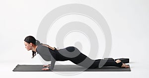 Athletic woman practicing yoga, performing transitions in the Marjariasana exercise, cat pose
