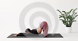 An athletic woman practicing yoga performs exercises with the transition from Anahatasana with Padmasana to Bhujangasana