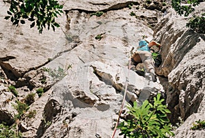 Athletic Woman in protective helmet and shoes on cliff rock wall lead climbing using rope and climbing harness in Paklenica