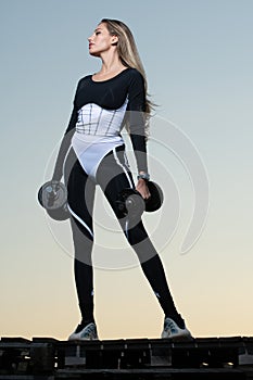 Athletic woman pumping up muscles with dumbbells. Woman sport body. Female muscular girl. Sexy woman working out with