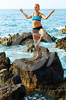 Athletic woman relaxing - practicing yoga on the rocks by the se