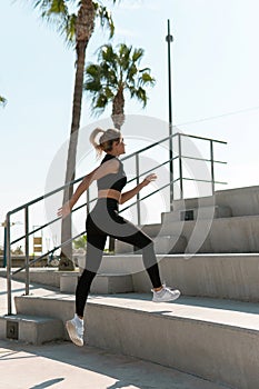 Athletic woman is running on concrete stairs during her summer workout