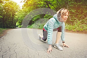 Athletic woman running in countryside road. Fitness female runner in ready start line pose outdoors in summer sprint