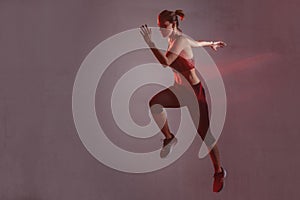 Athletic woman running forward in the studio