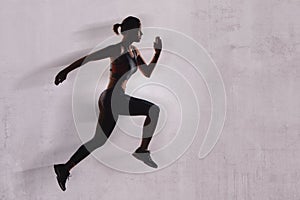 Athletic woman running forward in the studio