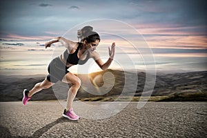 Athletic woman runs on the street during sunset