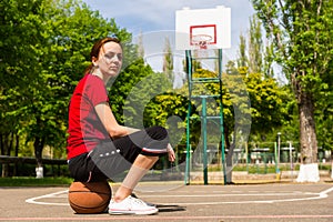 Athletic Woman Sitting on Basketball on Court