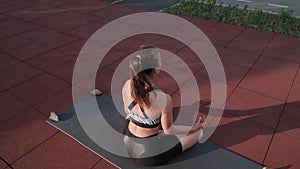 Athletic Woman Sitting in lotus position and Doing Yoga Lake Background. Beautiful Girl Exercising Outdoors. Stretching Exercises