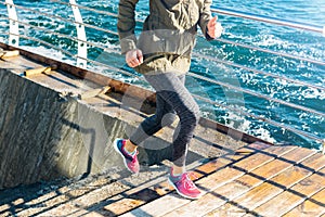 Athletic woman in sports clothes runs up the stairs in sneakers