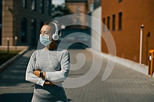 Athletic woman in sportswear listening to music using headphones and looking aside during Covid 19 pandemic