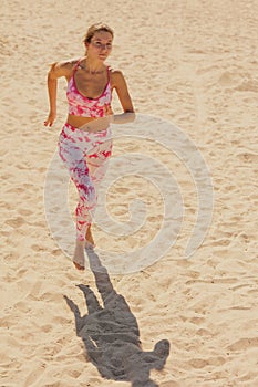 athletic woman in sportswear runs along sandy beach. sporty lady prepares for marathon