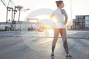 Athletic woman standing in industrial area. Resting after nice workout. Sporty and fit body