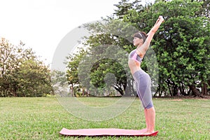 Athletic woman streching. Girl is exercising on yoga mat. Lifestyle and sport concept in a wooded area.