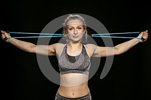 Athletic woman stretches elastic rubber behind her head, close u