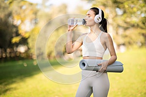 An athletic woman in stylish sportswear hydrates while drinking from a water bottle photo