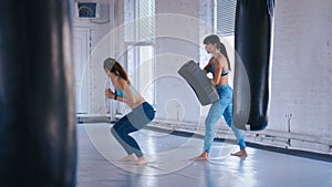 Athletic Woman Trains Her Kicks on a Punching Bag that Her Partner Holds. Training of Taekwondo or Kickboxing. Two