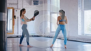 Athletic Woman Trains Her Kicks on a Punching Bag that Her Partner Holds. Training of Taekwondo or Kickboxing. Two