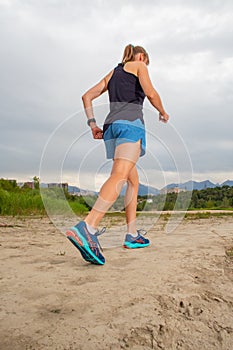 Athletic woman warming up before her morning workout in the forest mountain road. Runner training outdoors, healthy