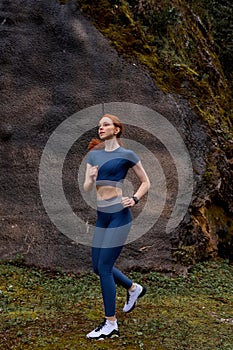 Athletic woman warms up in park mountains before jogging. Healthy lifestyle concept.