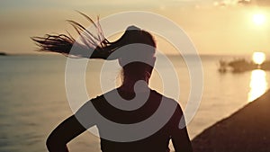 Athletic woman with waving hair running on beach at dramatic sun. Medium shot on RED camera