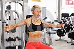 Athletic women training chest on a simulator at gym