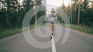 Athletic youg woman Jogging in a park. Stedycam shot.