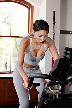 Athletic young biracial woman doing cardio workout on exercise bike at the gym