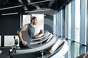Athletic Young Black Man Jogging On Modern Treadmill At Gym