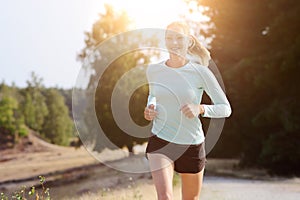 Athletic young blonde woman jogging, running and training outdoors on a sunny day in summer