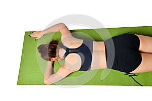 Athletic young girl lies face down on a yoga mat and stretches her arms forward in front of her