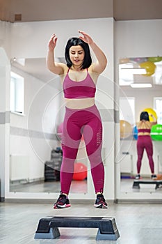 Athletic young girl practicing on the stepper in the gym. The concept of sports, a healthy lifestyle, losing weight