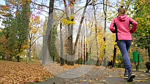 Athletic young girl running in autumn Park after rain. rear view