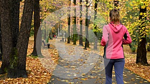Athletic young girl running in autumn Park after rain. rear view